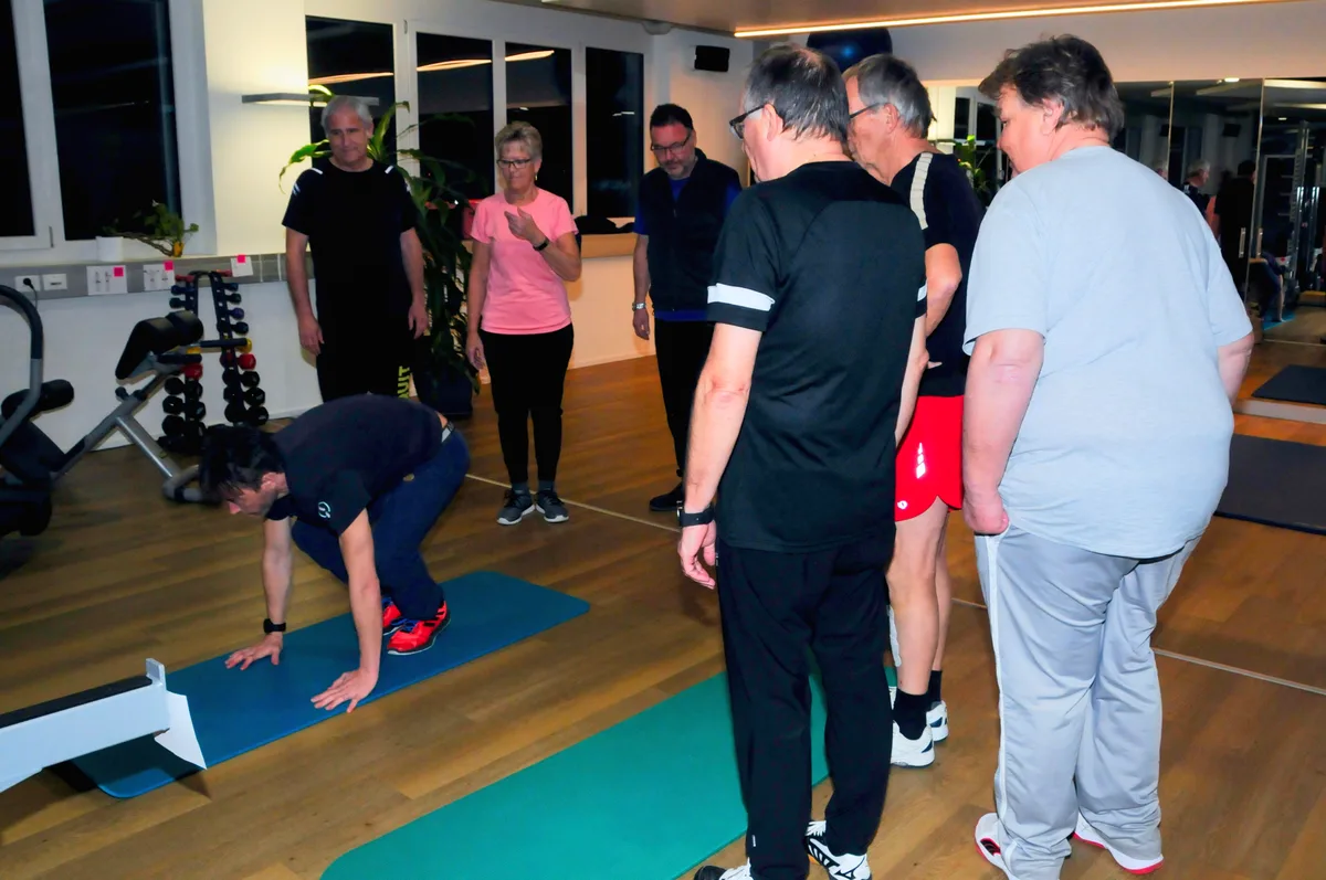 Man sieht einen Trainer, der einer Gruppe Trainingsanweisungen erteilt.